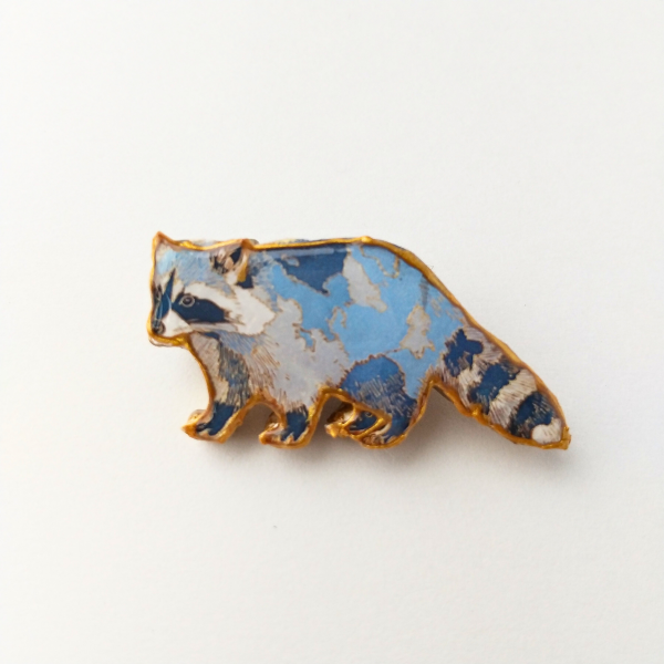 金の輪郭とレジンのアライグマのブローチ